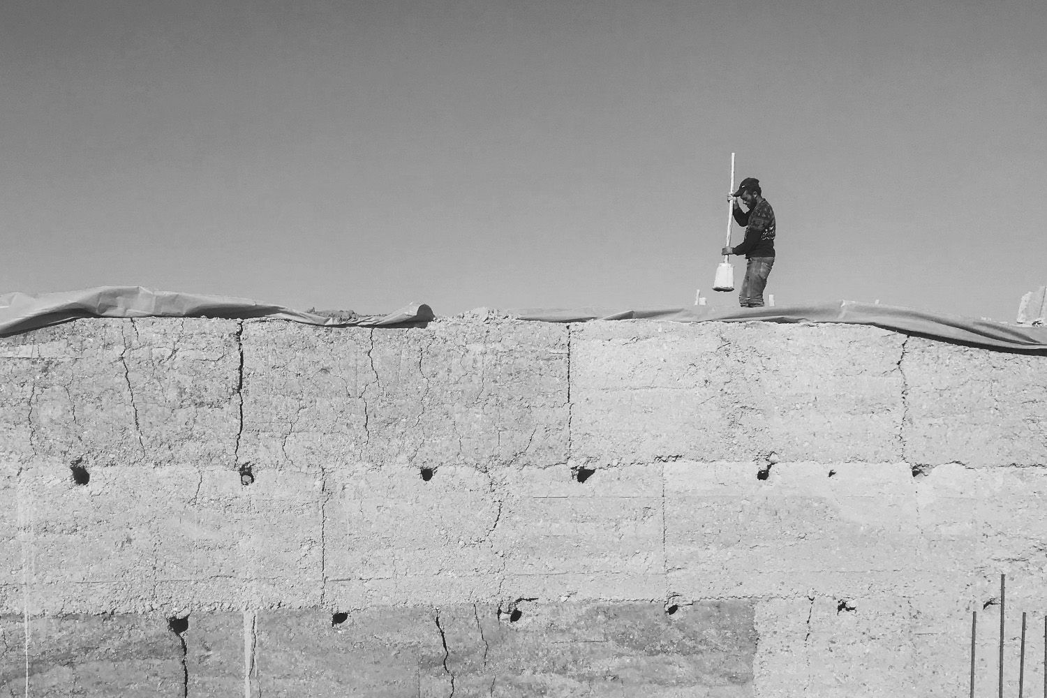 Artisan damant la terre au sommet d'un mur en pisé