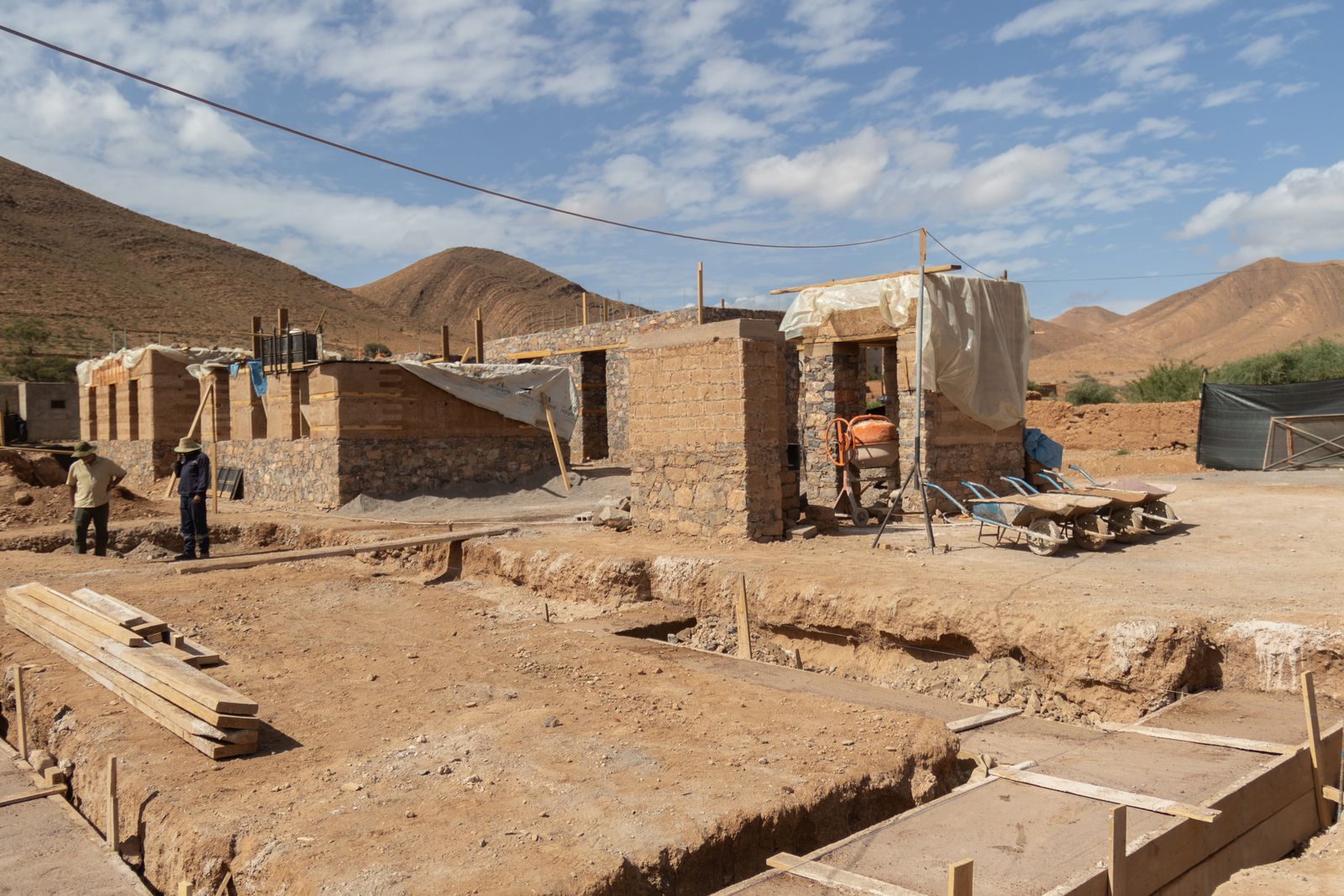 Le chantier au pied des montagnes, murs en pierre et en pisé