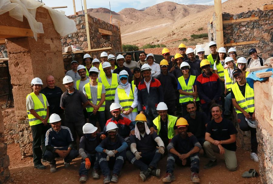 Artisans et étudiants réunis entre les murs en pierre et en terre du chantier