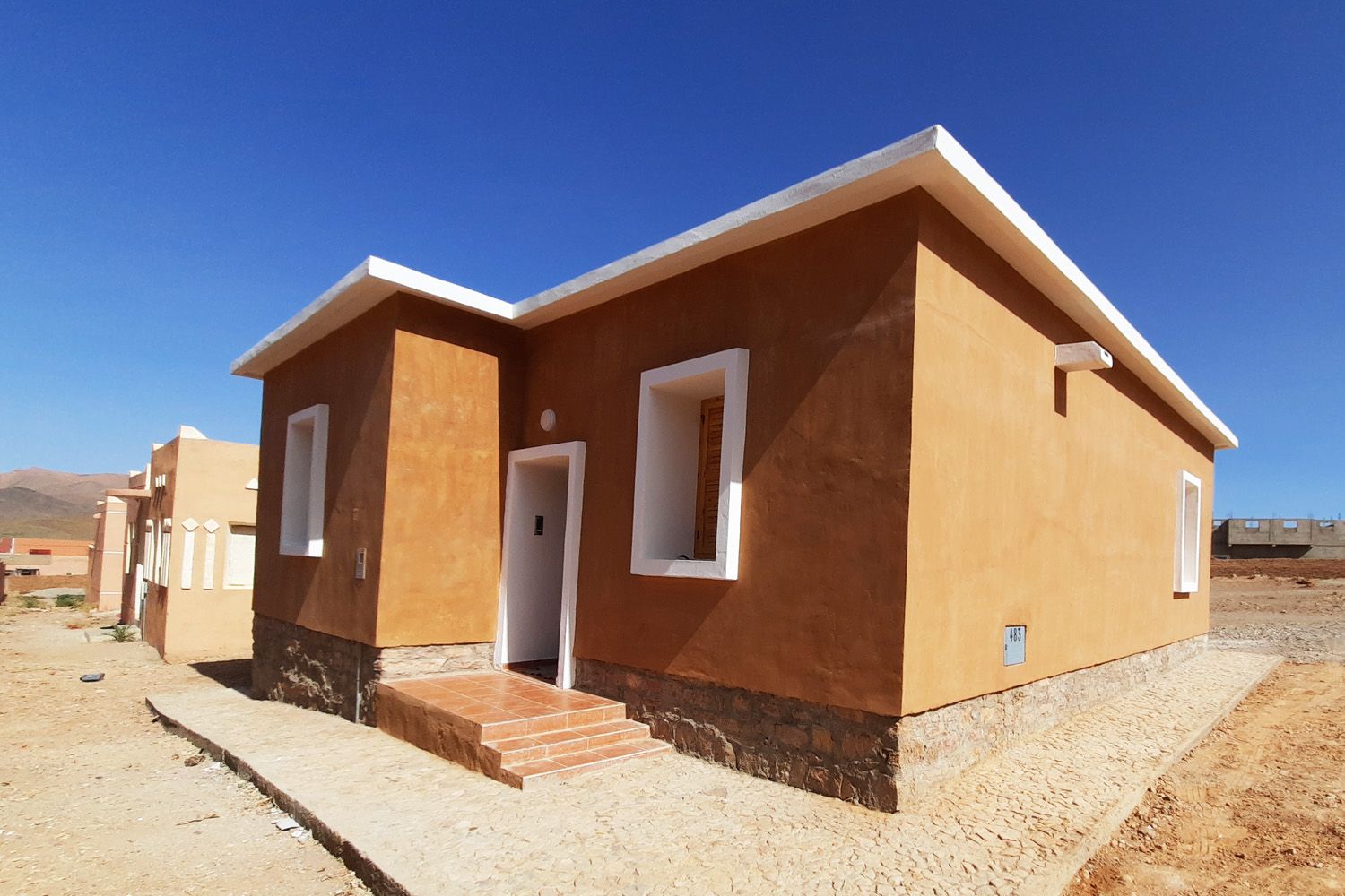 Logement en pisé vu en perspective, montagnes au loin